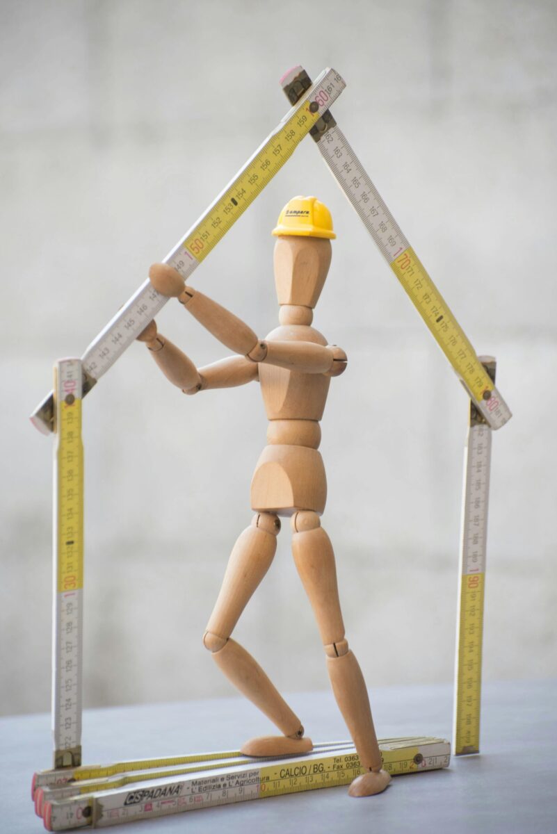 Artistic representation of a construction theme using a wooden mannequin and folding rulers.